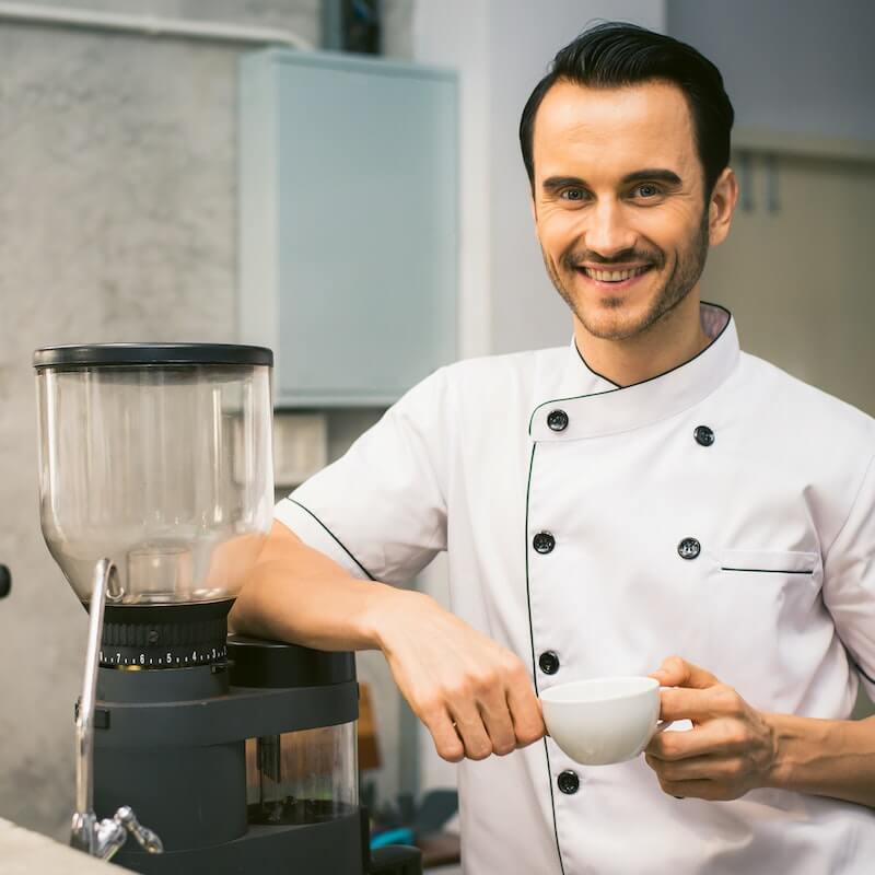 A chef is smiling and wearing a white dress